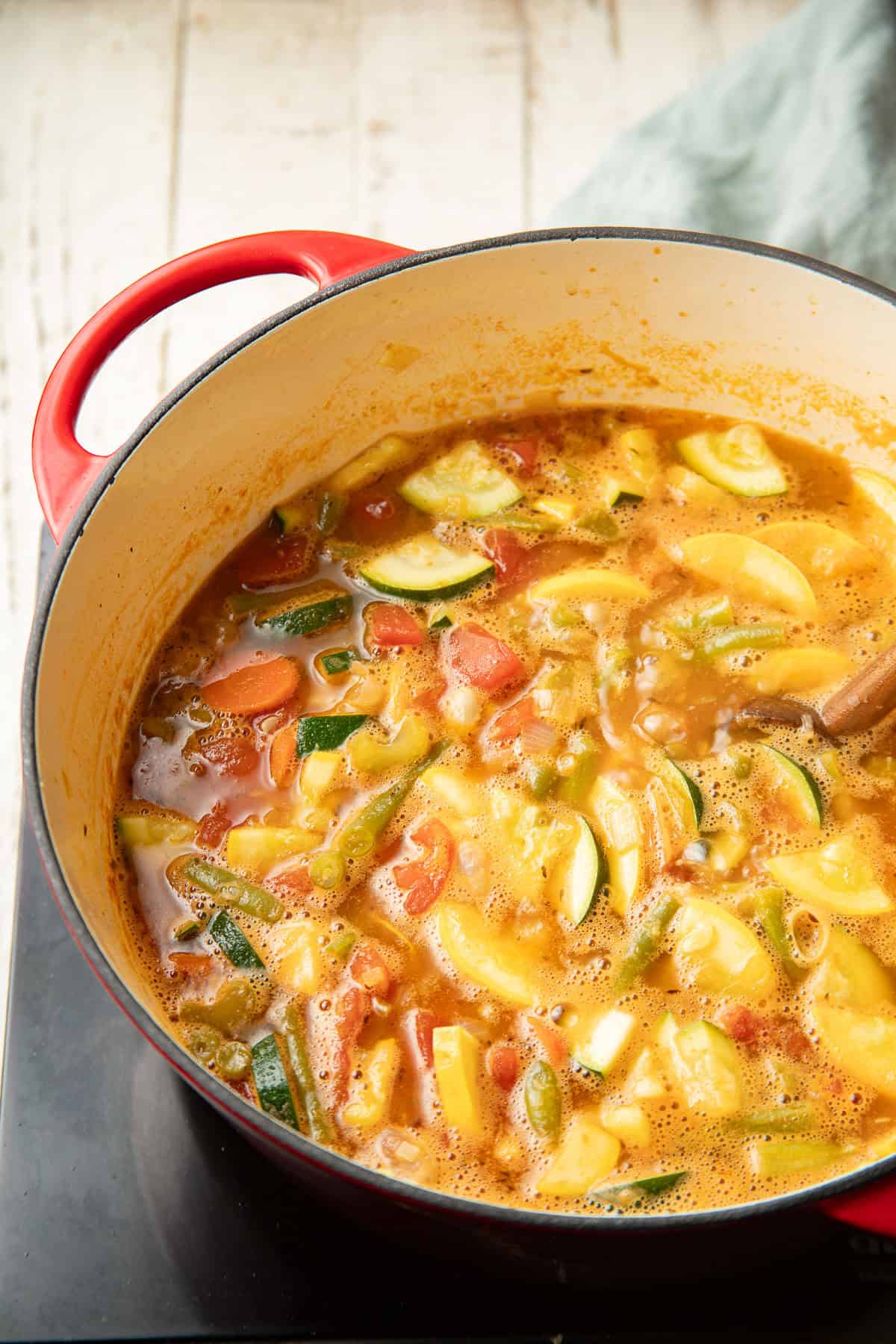 Vegetable soup in a pot on a cooktop.
