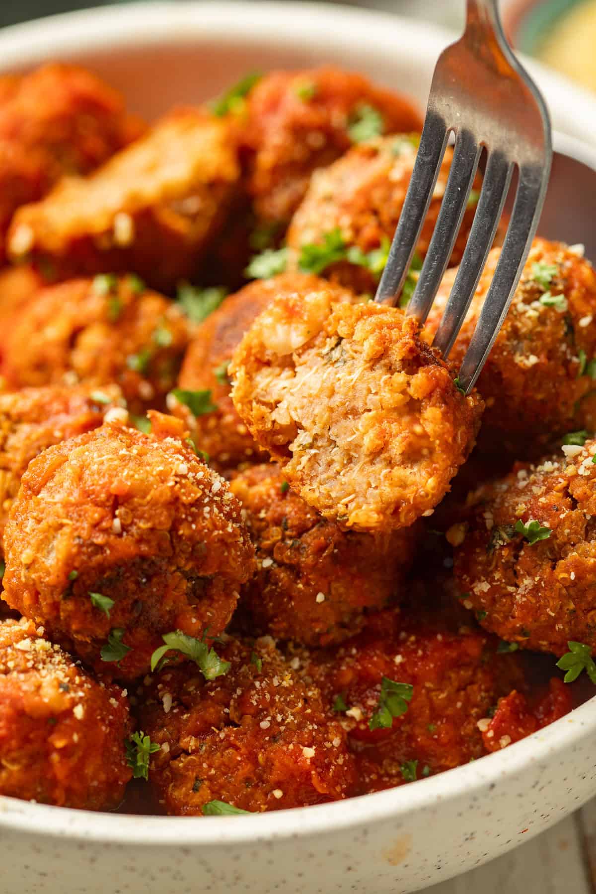 Bowl of Quinoa Meatballs with a fork stabbing a half of a meatball.