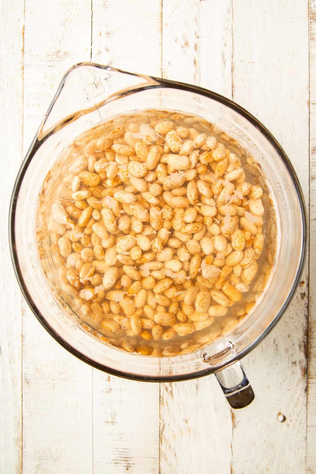 Pinto beans soaking in a bowl of water.
