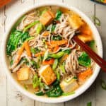 Bowl of soba noodle soup with chopsticks.