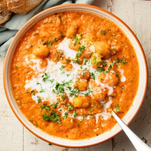 Bowl of Tomato Basil Gnocchi Soup topped with coconut milk and parsley.