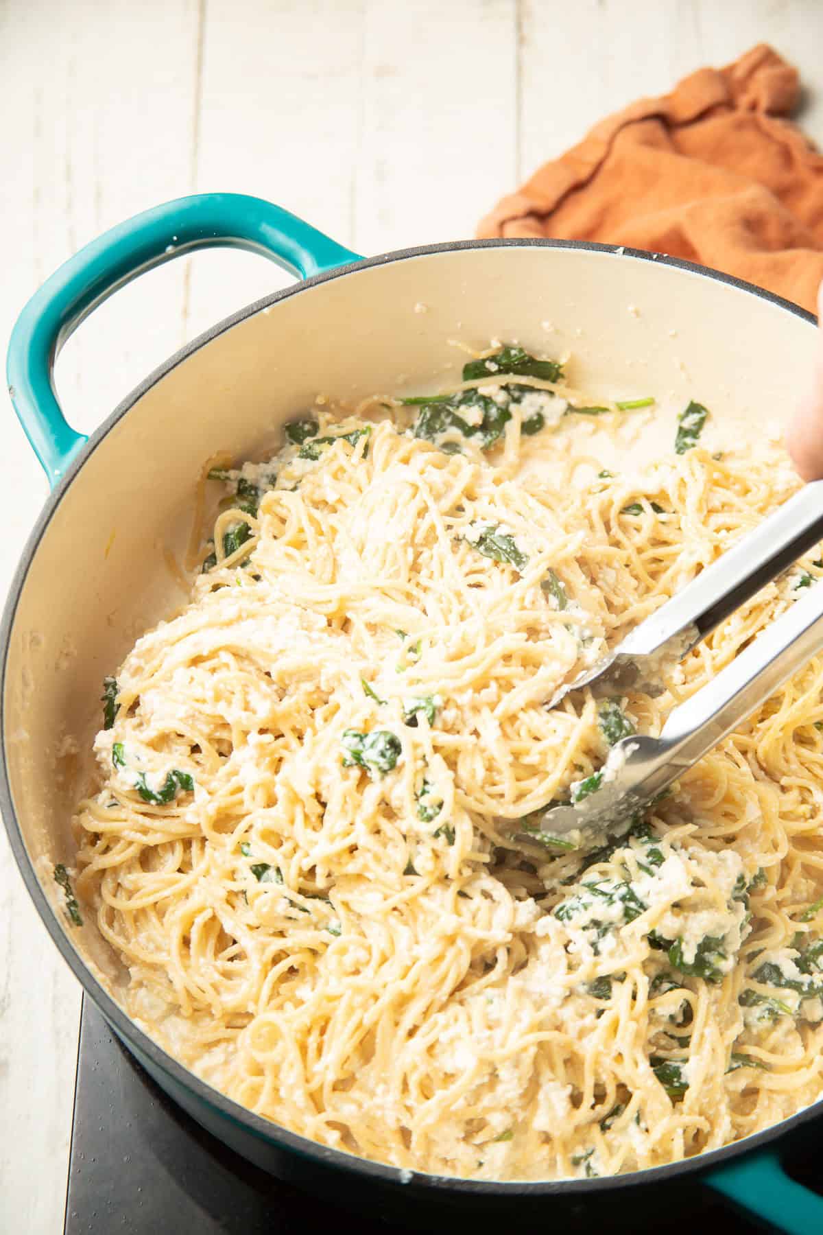 Vegan Lemon Ricotta Pasta cooking in a pot and being tossed with tongs.