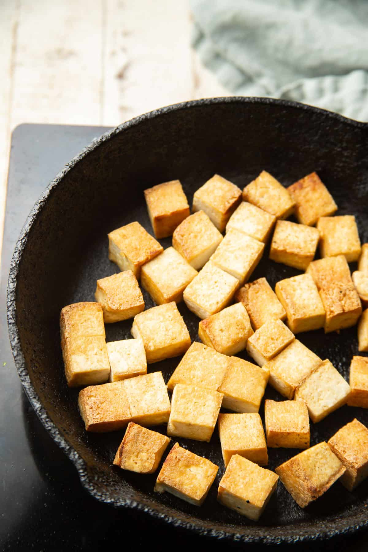 Tofu cubes cooking in a skillet.