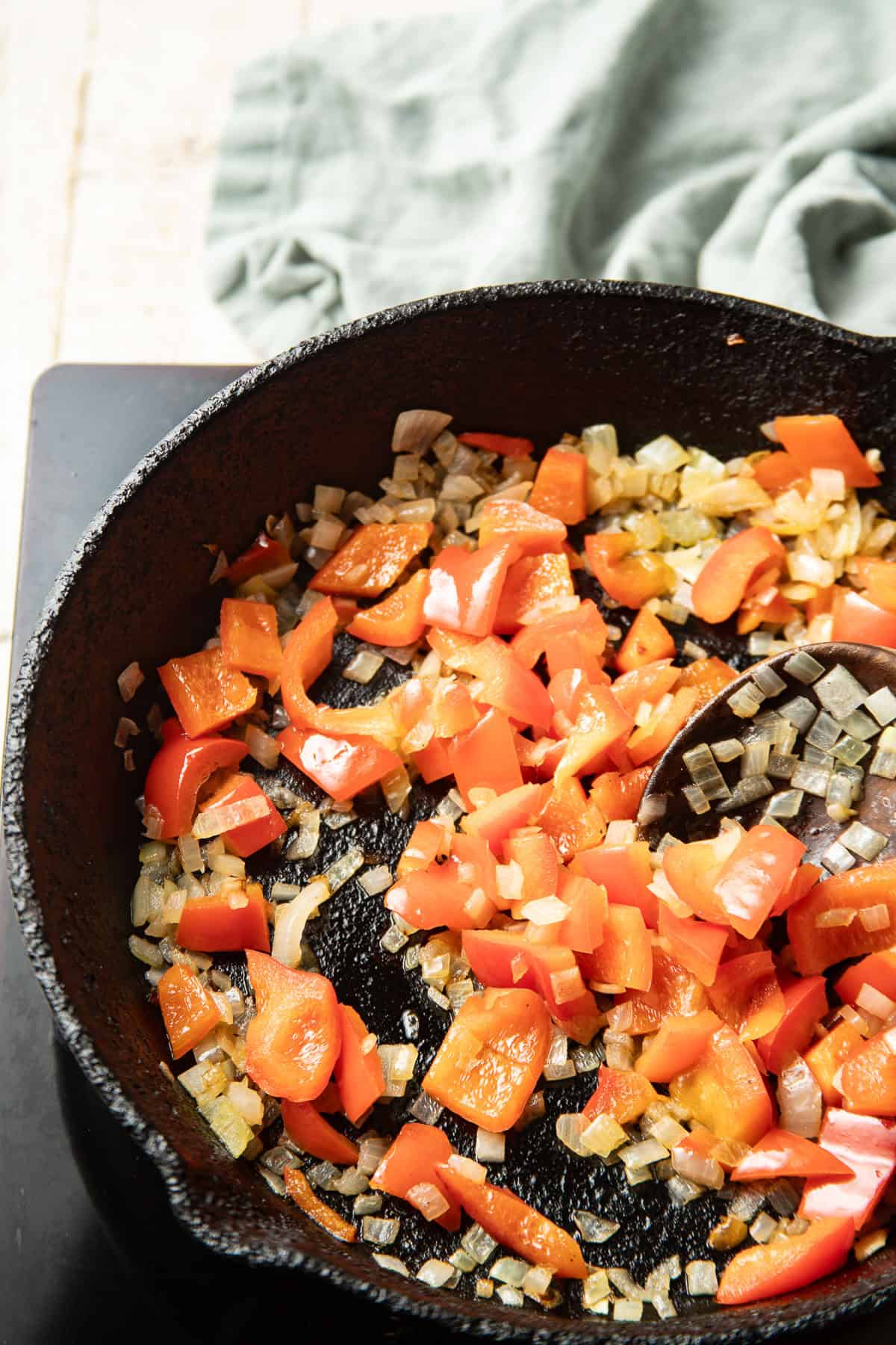 Diced onions and peppers cooking in a skillet.