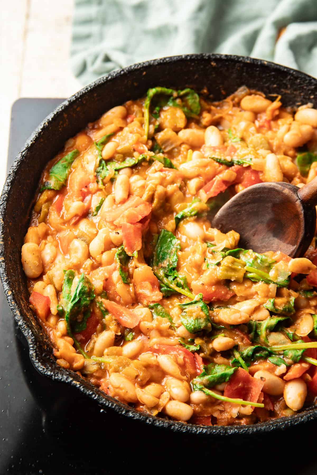 Creamy white beans and kale simmering in a skillet.