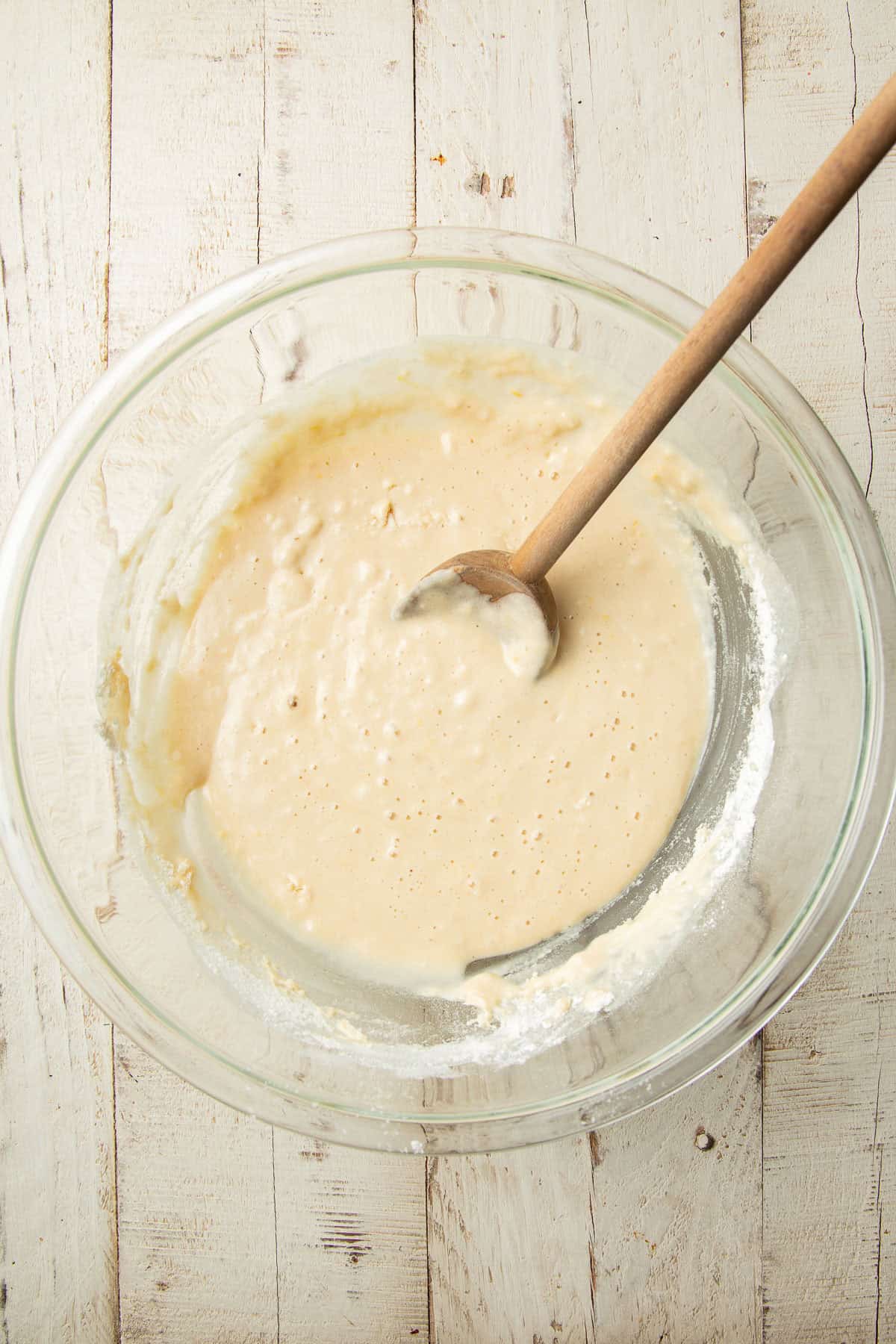 Cake batter in a mixing bowl with wooden spoon.