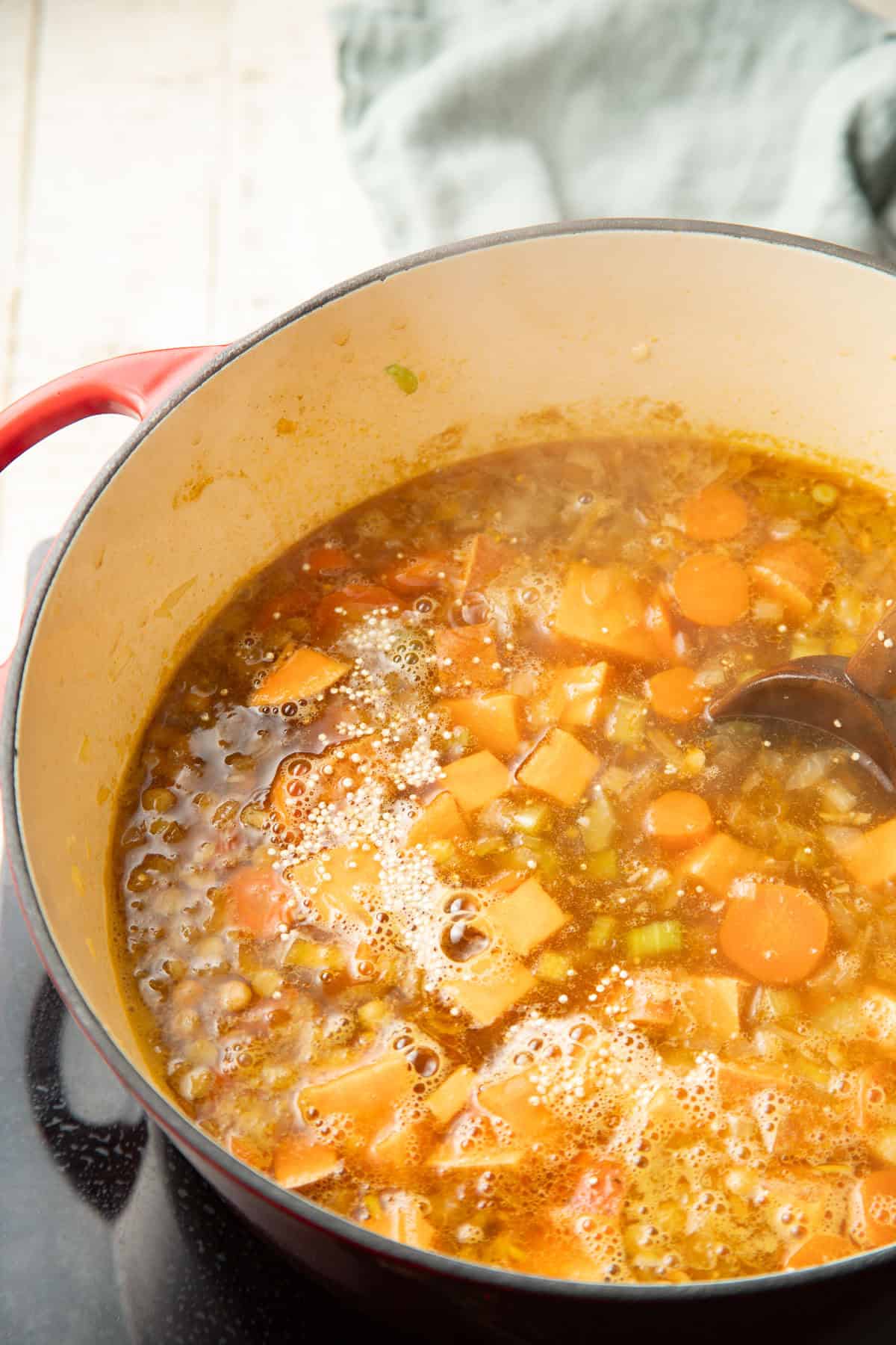 Quinoa, vegetables, and lentils simmering in broth.