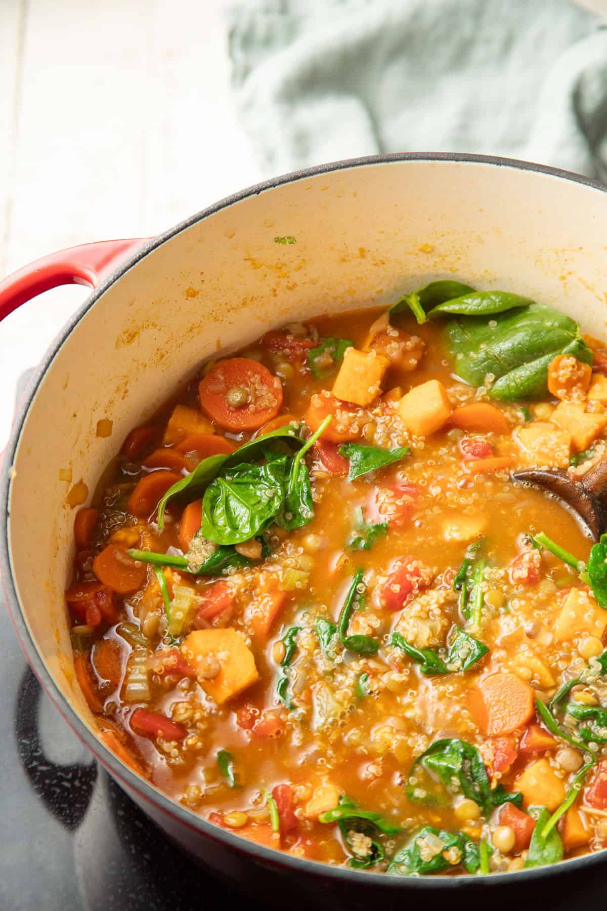 Quinoa soup simmering in a pot on a cooktop.