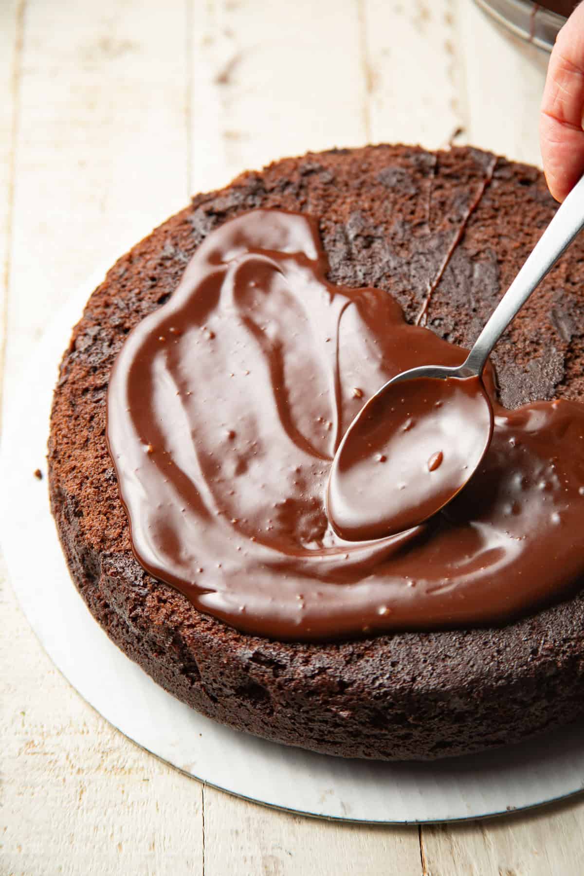 Spoon spreading ganache over a Vegan Chocolate Olive Oil Cake.