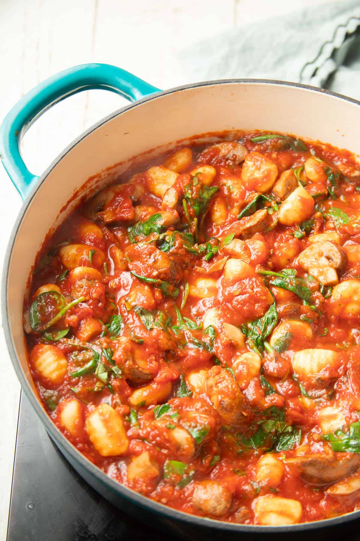 Gnocchi, mushrooms, and spinach in tomato sauce in a casserole dish.