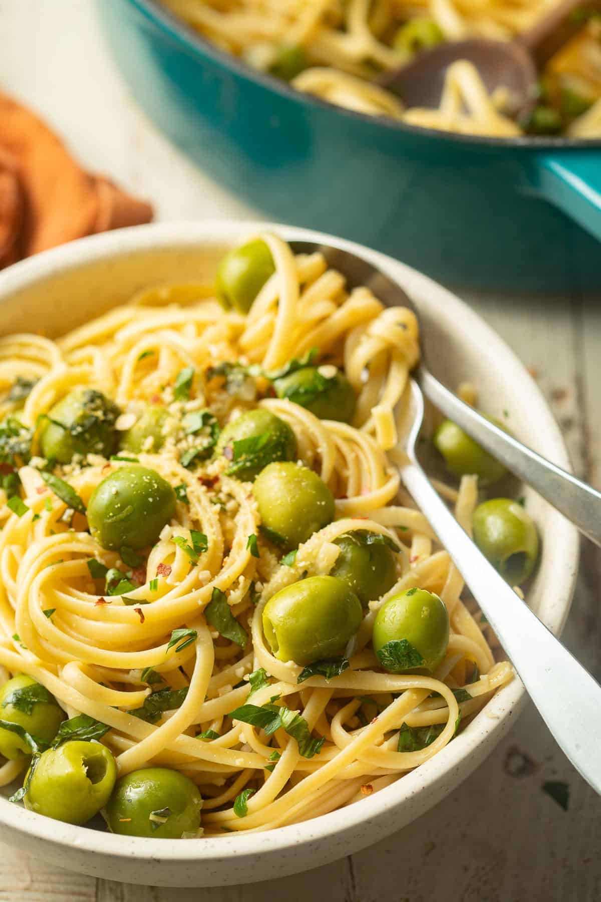 Bowl of Green Olive Pasta with a blue pot in the background,