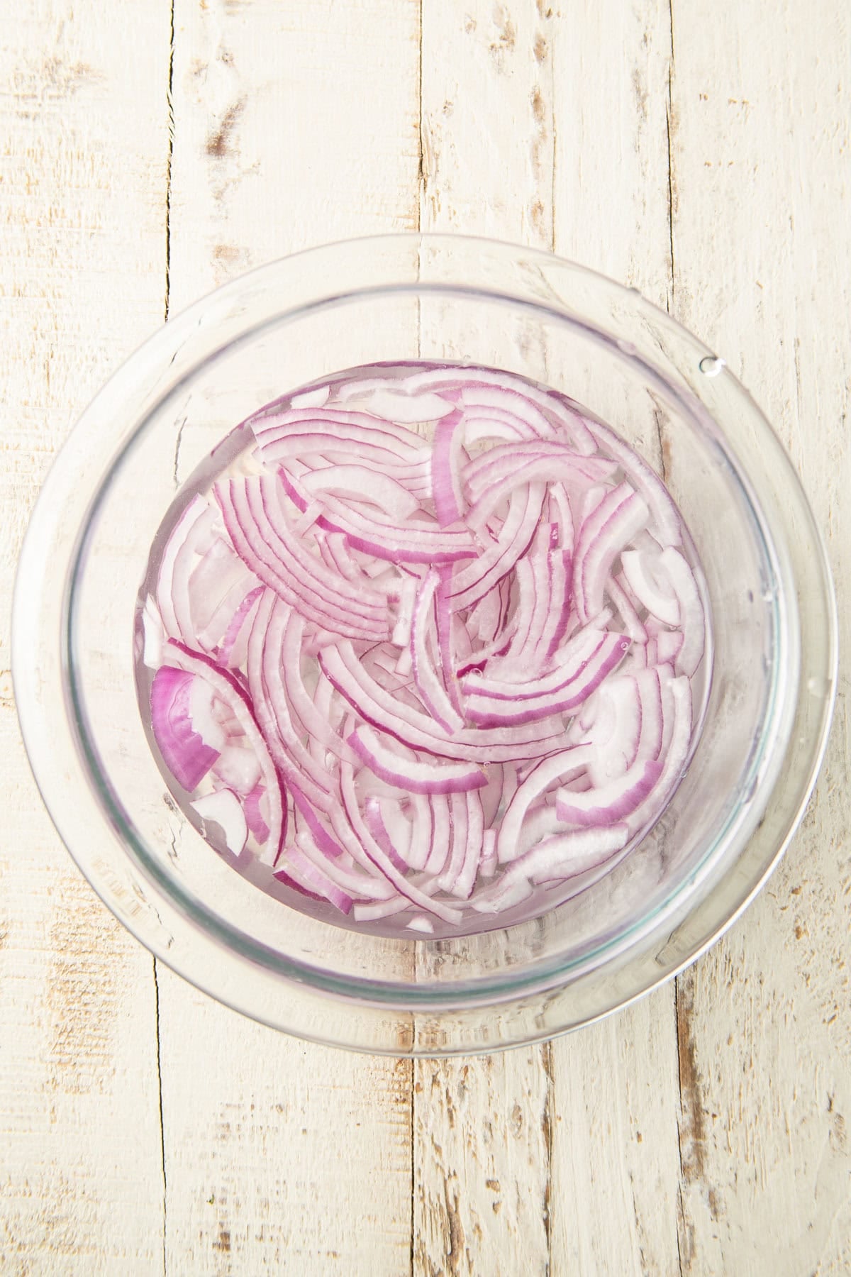 Red onion slices soaking in a bowl of water.