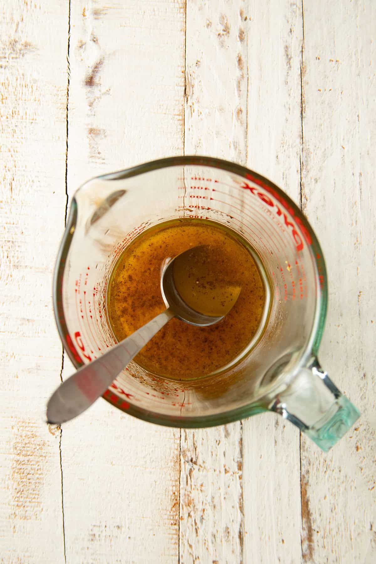 Lemon vinaigrette in a liquid measuring cup with spoon.