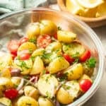 Bowl of Mediterranean Potato Salad with lemons in the background.