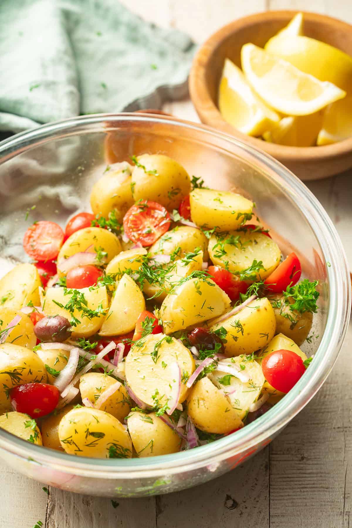 Bowl of Mediterranean Potato Salad with lemons in the background.