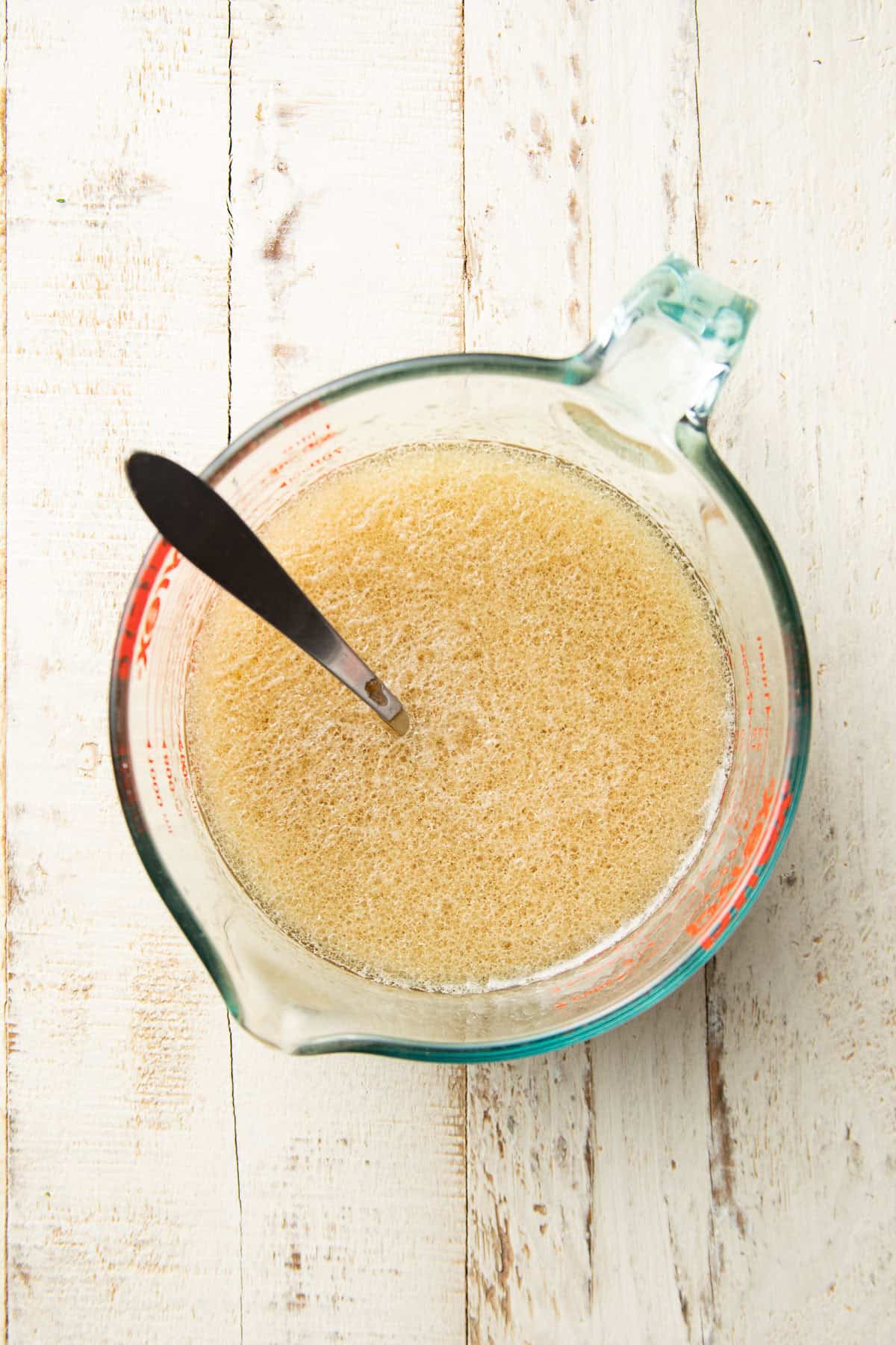 Wet ingredients for cake in a liquid measuring cup with spoon.