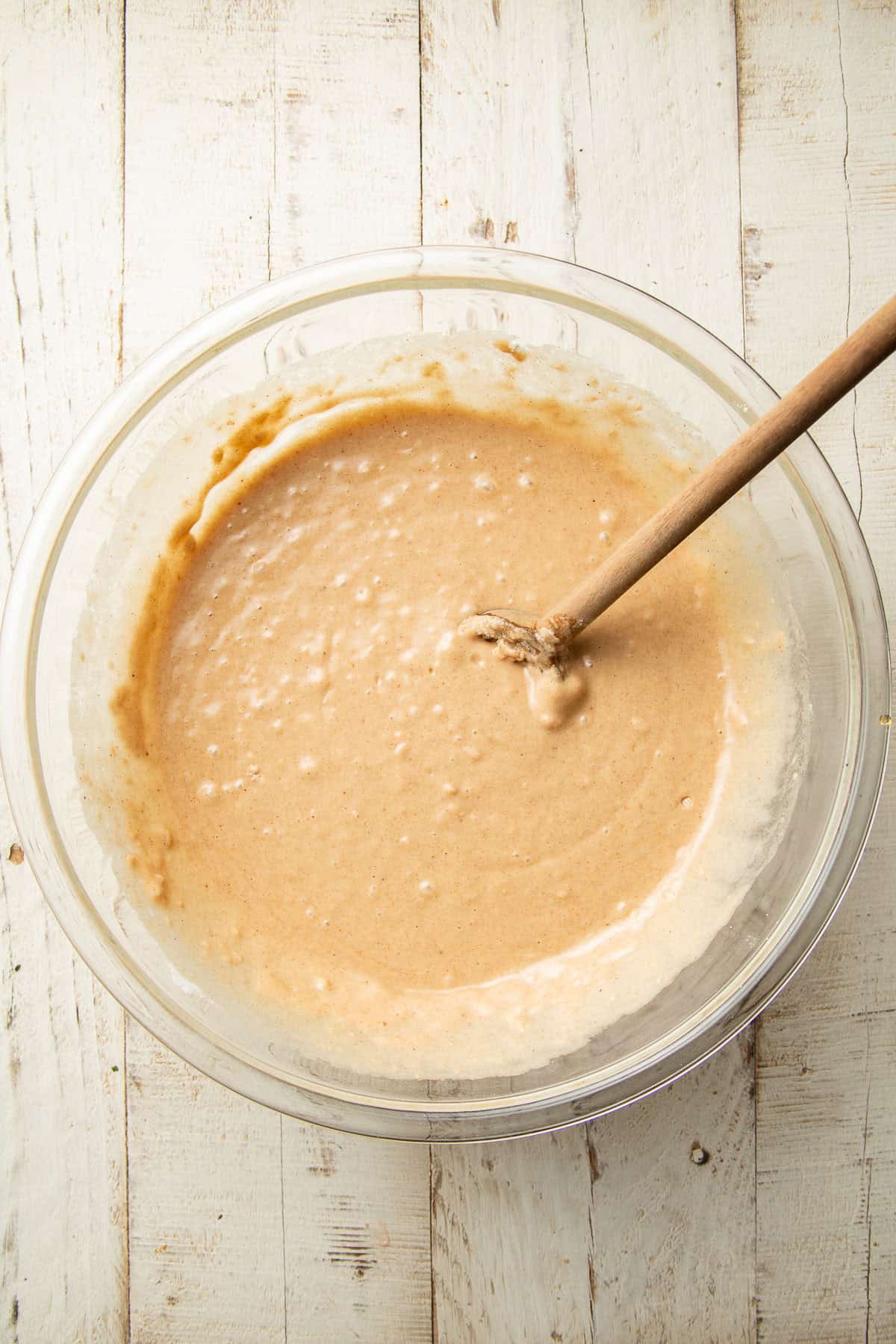 Cake batter in a mixing bowl with wooden spoon.