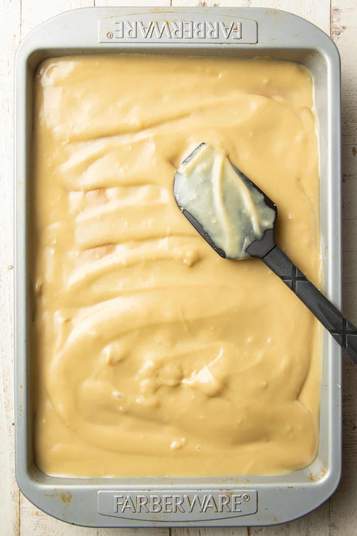 Rectangular cake covered with a layer of butterscotch pudding.
