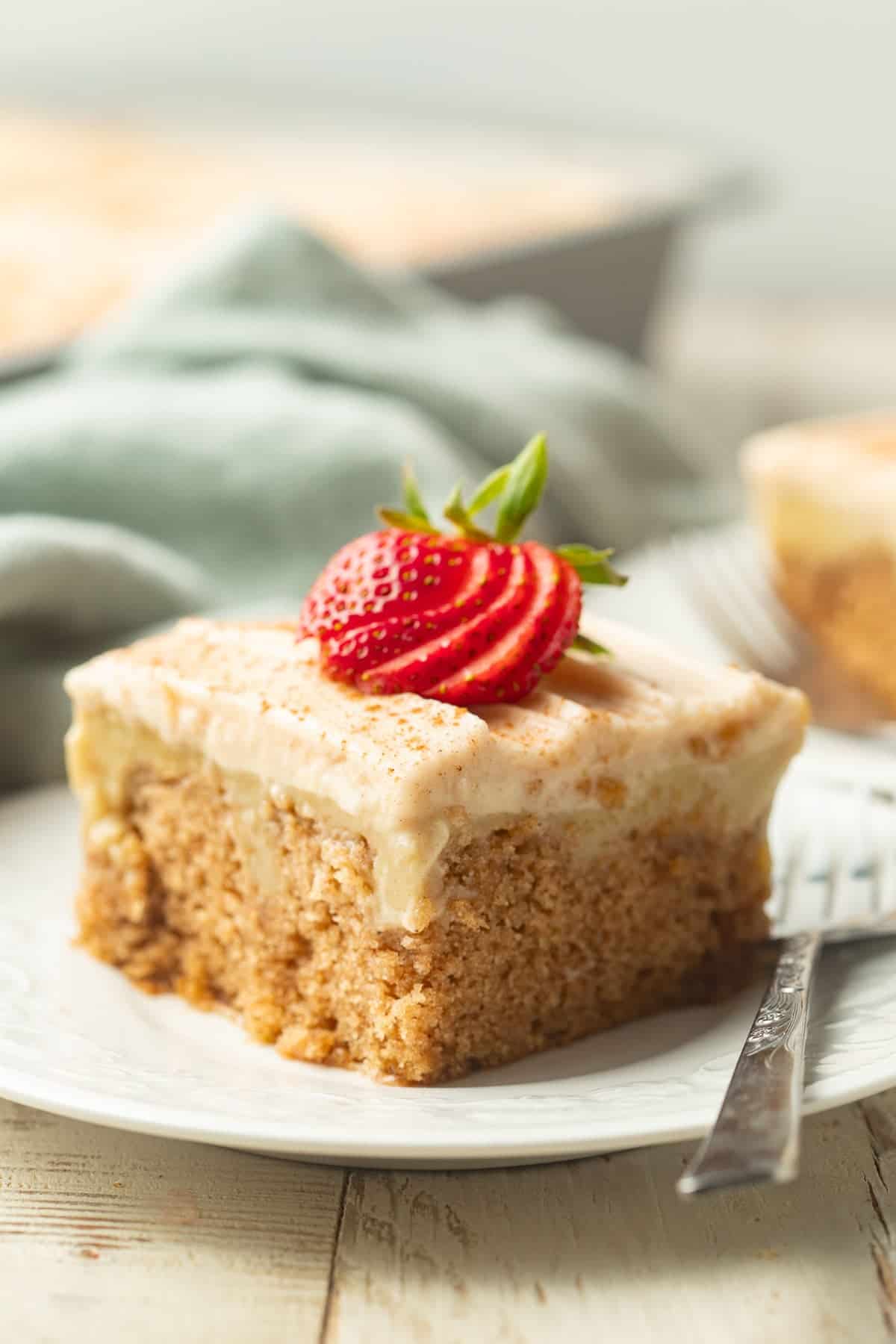 Slice of vegan poke cake with cake pan and second slice in the background.