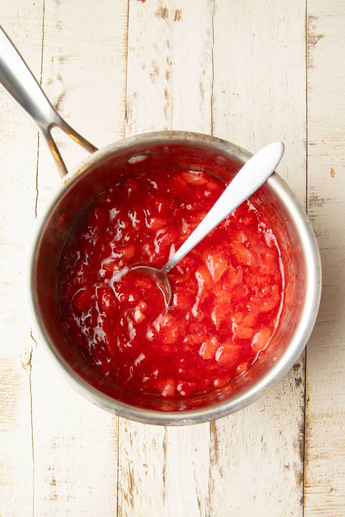 Vegan Strawberry Roll filling in a saucepan with spoon.