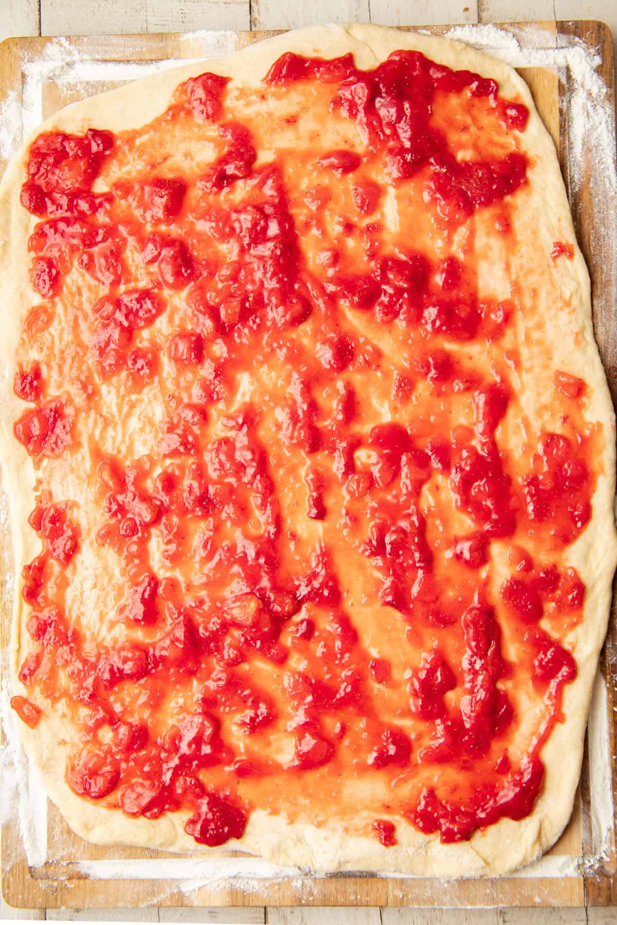 Rolled out dough rectangle covered with strawberry filling.