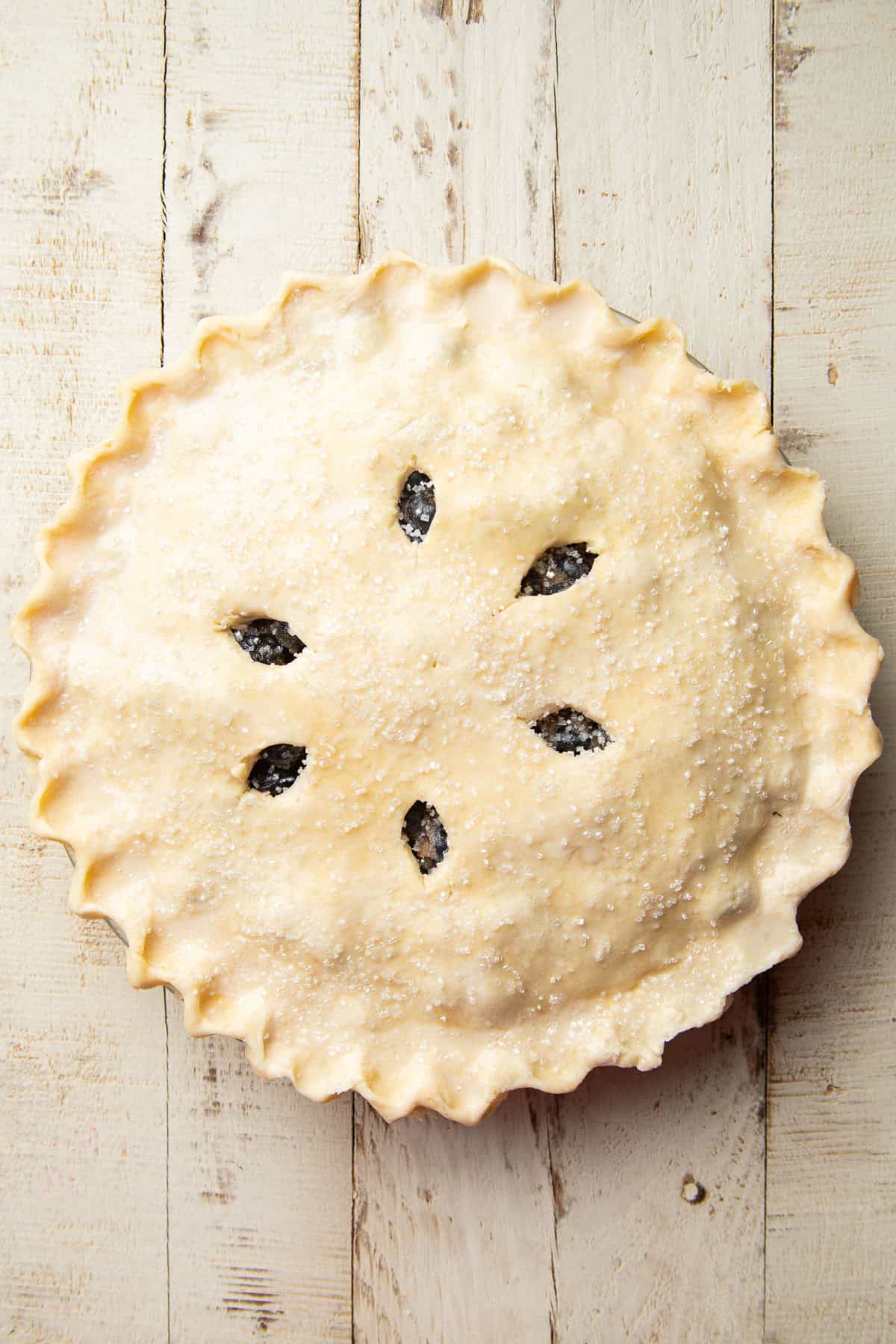 Unbaked Vegan Blueberry Pie on a white wooden surface.