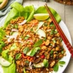 White wooden surface set with a wok and plat of Vegan Larb.