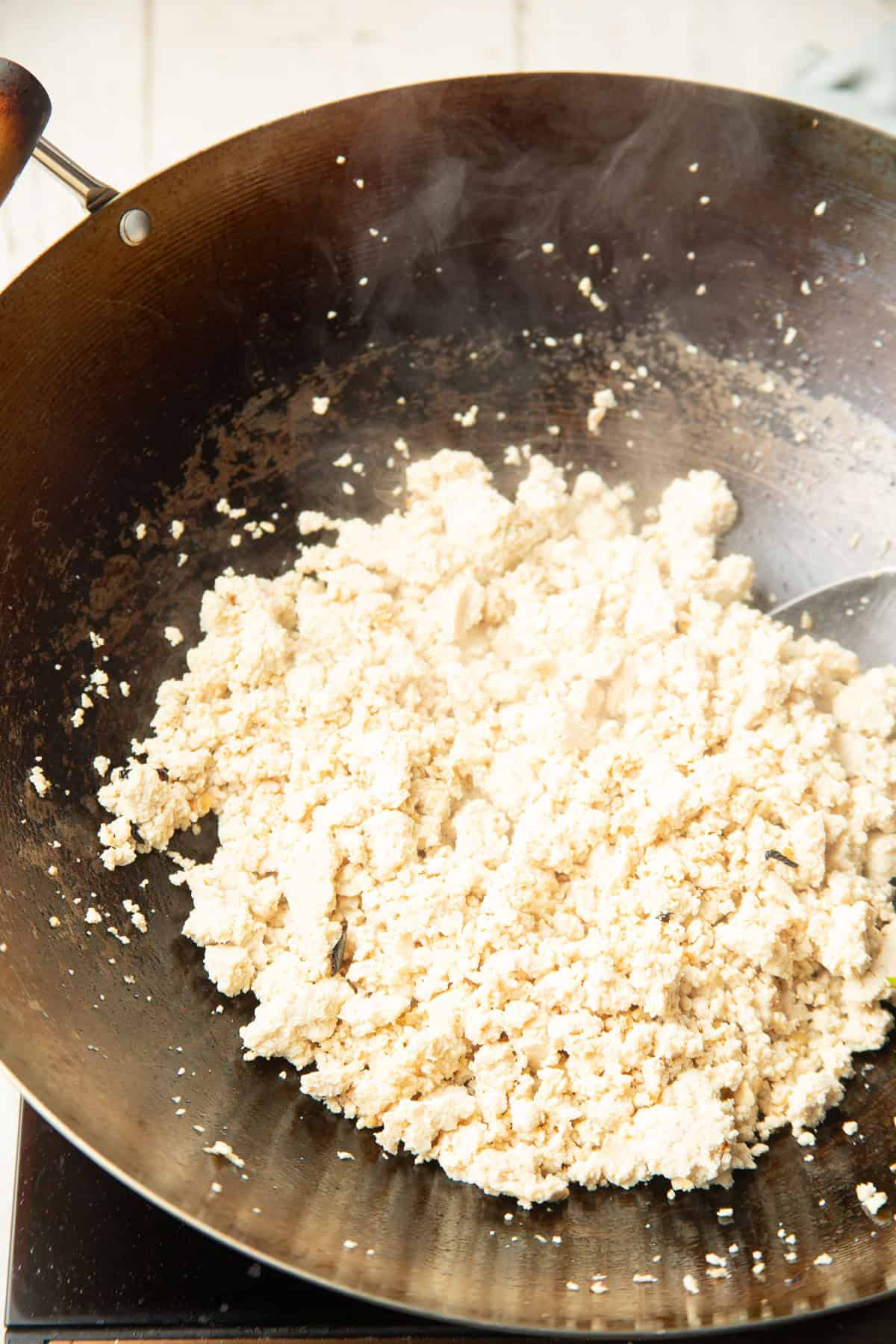 Crumbled tofu cooking in a wok.
