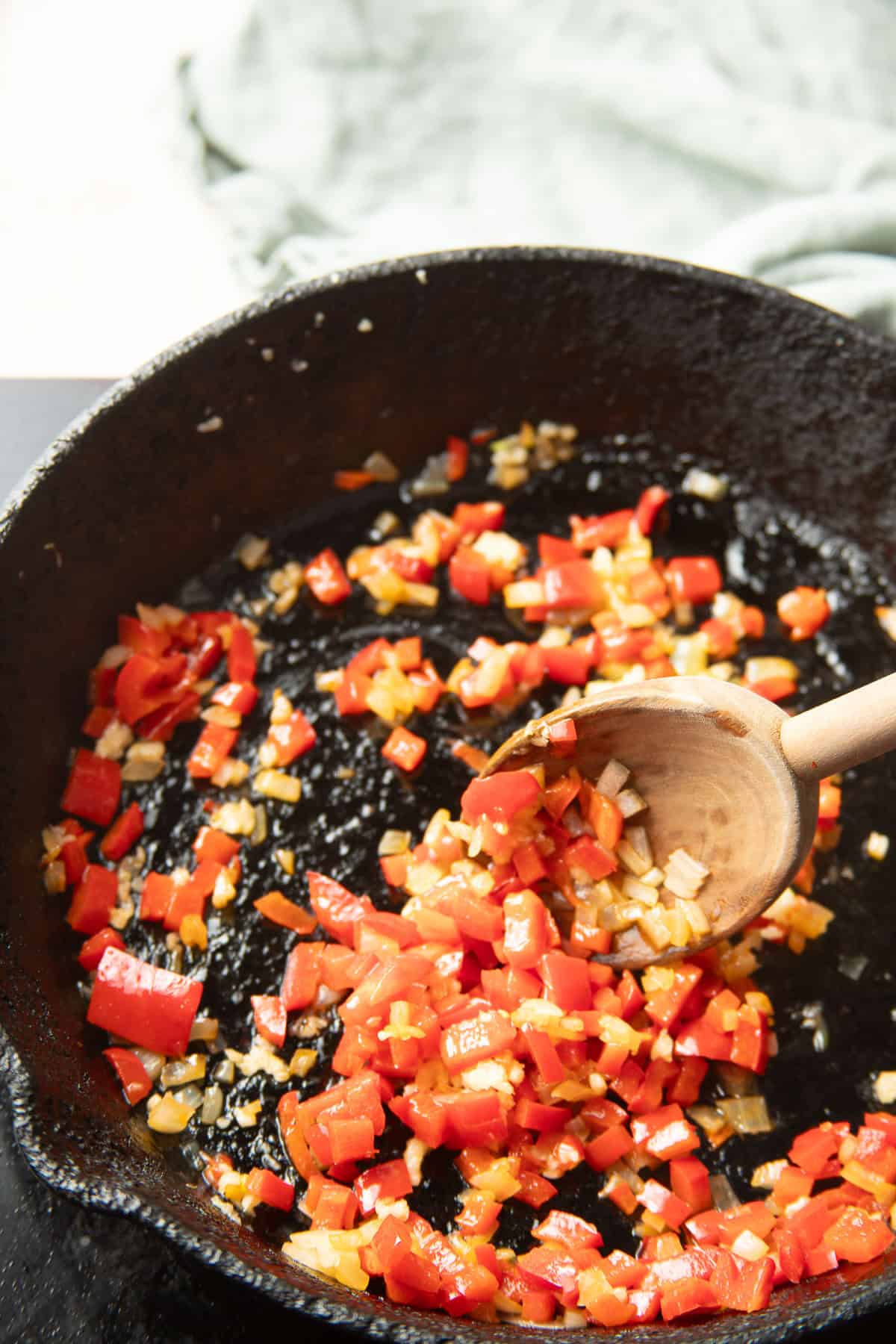 Diced peppers and onions cooking in a skillet.