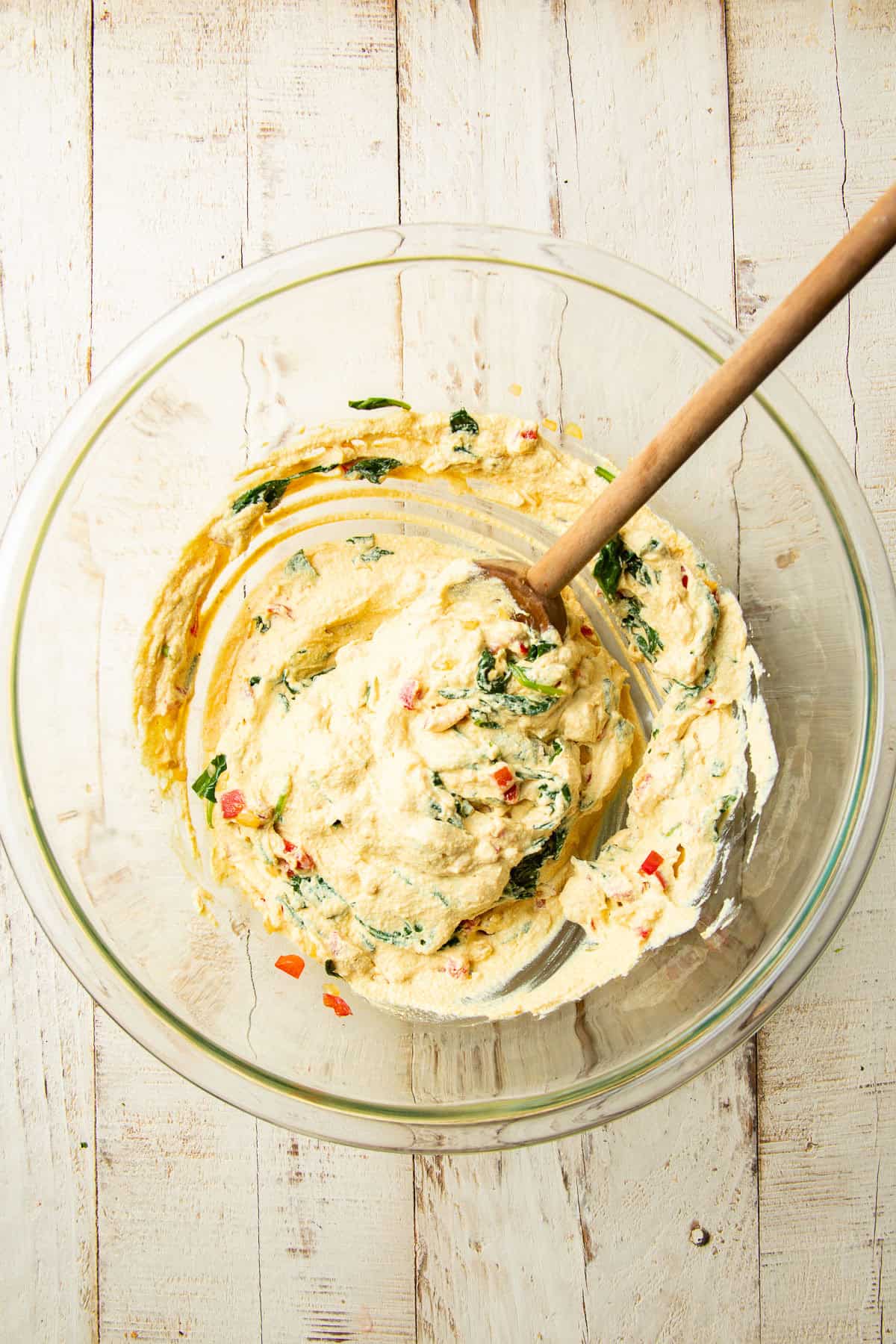 Vegan egg bite batter in a mixing bowl with veggies stirred in.