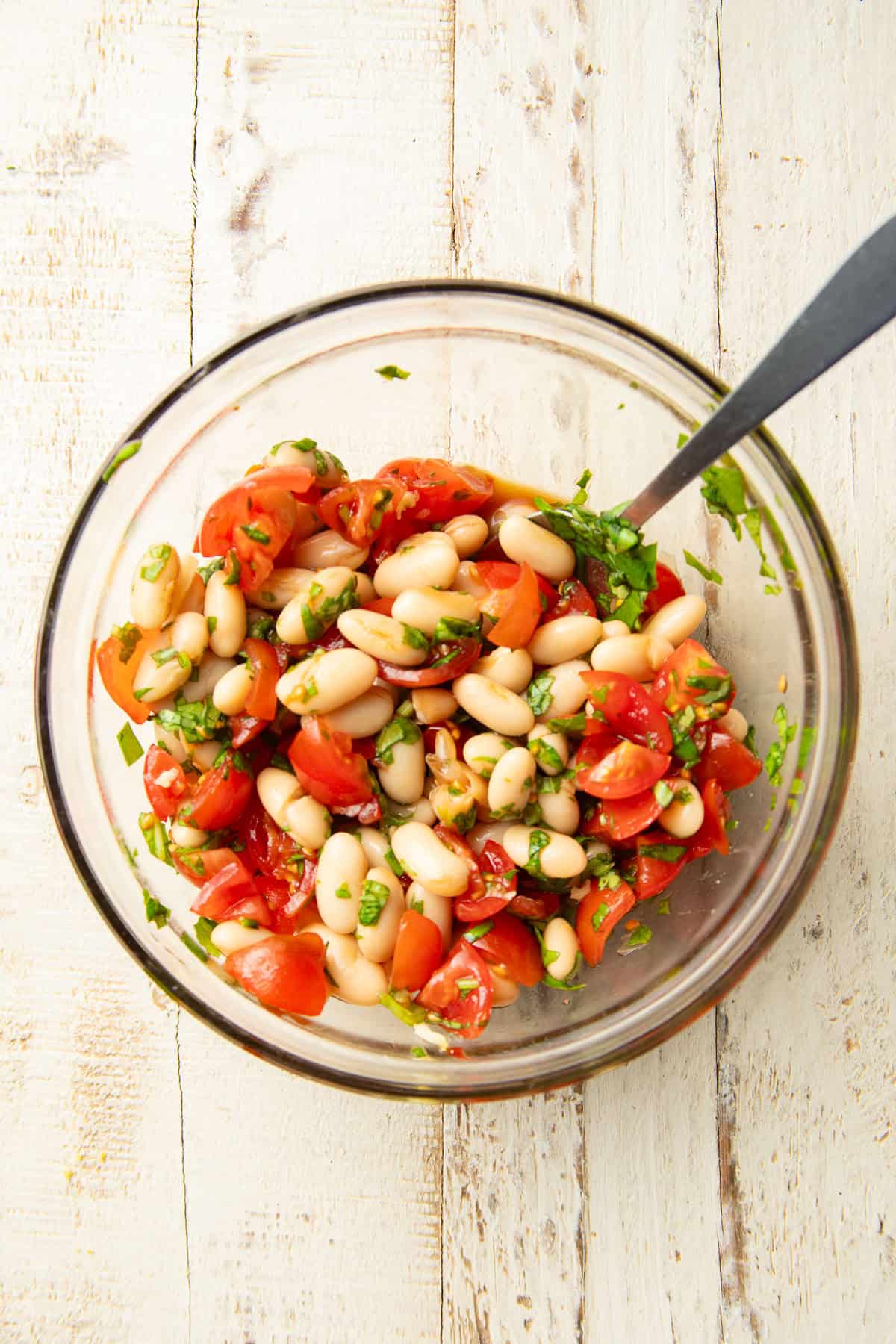 White bean tomato bruschetta in a bowl with spoon.
