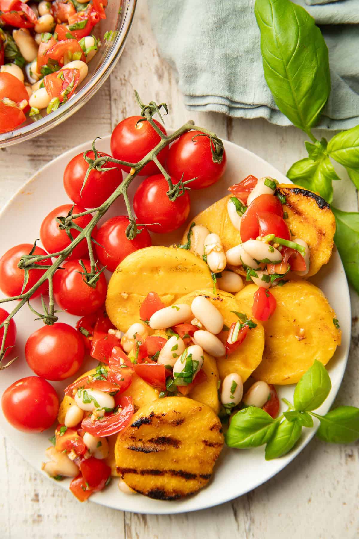 Grilled Polenta on a plate with cherry tomatoes and white bean bruschetta.