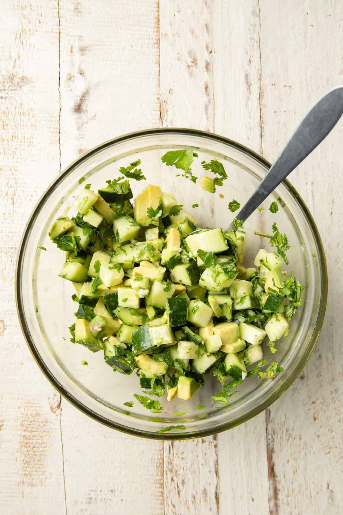 Avocado cucumber relish in a bowl with spoon.