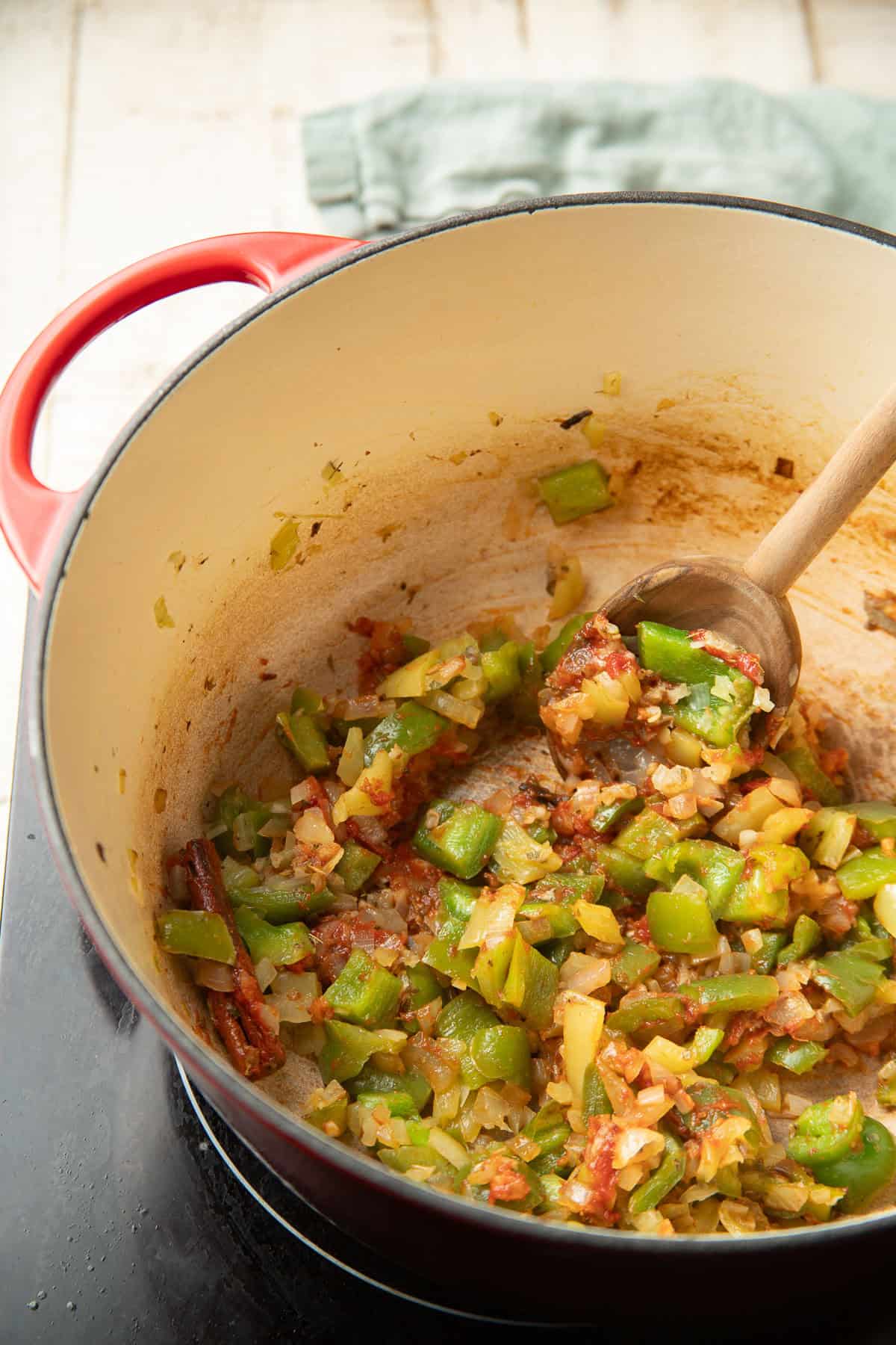 Diced peppers, onions, and spices cooking in a pot.