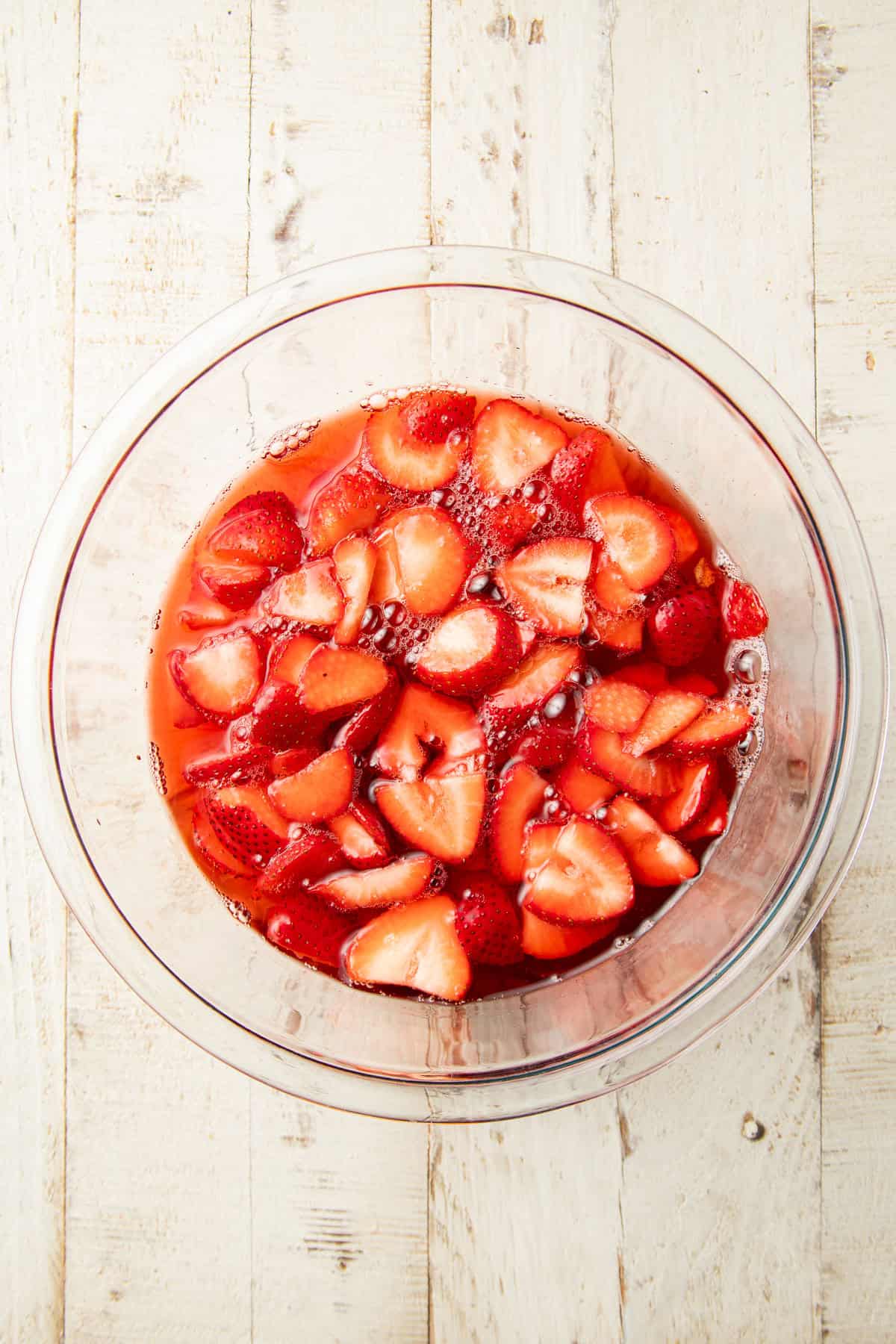 Bowl of unset vegan gelatin with fresh strawberries.