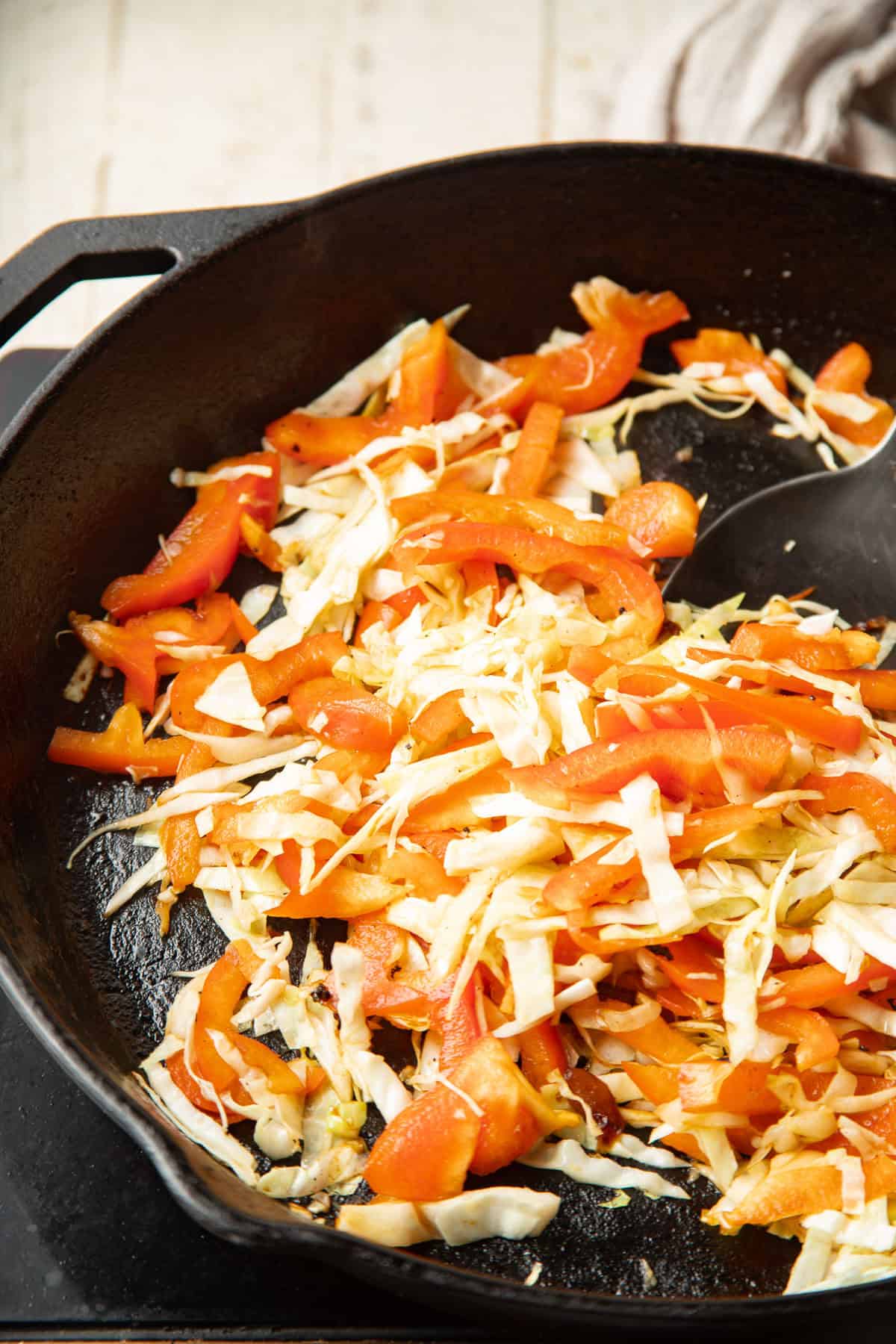 Cabbage and peppers cooking in a skillet.