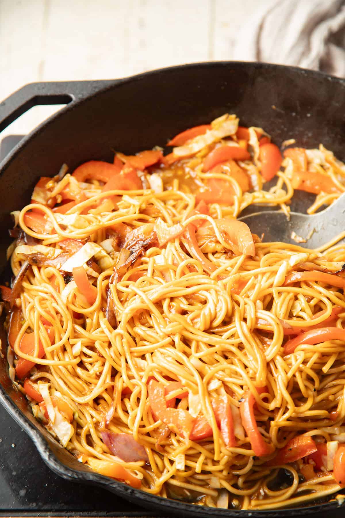 Peanut noodles and veggies cooking in a skillet.