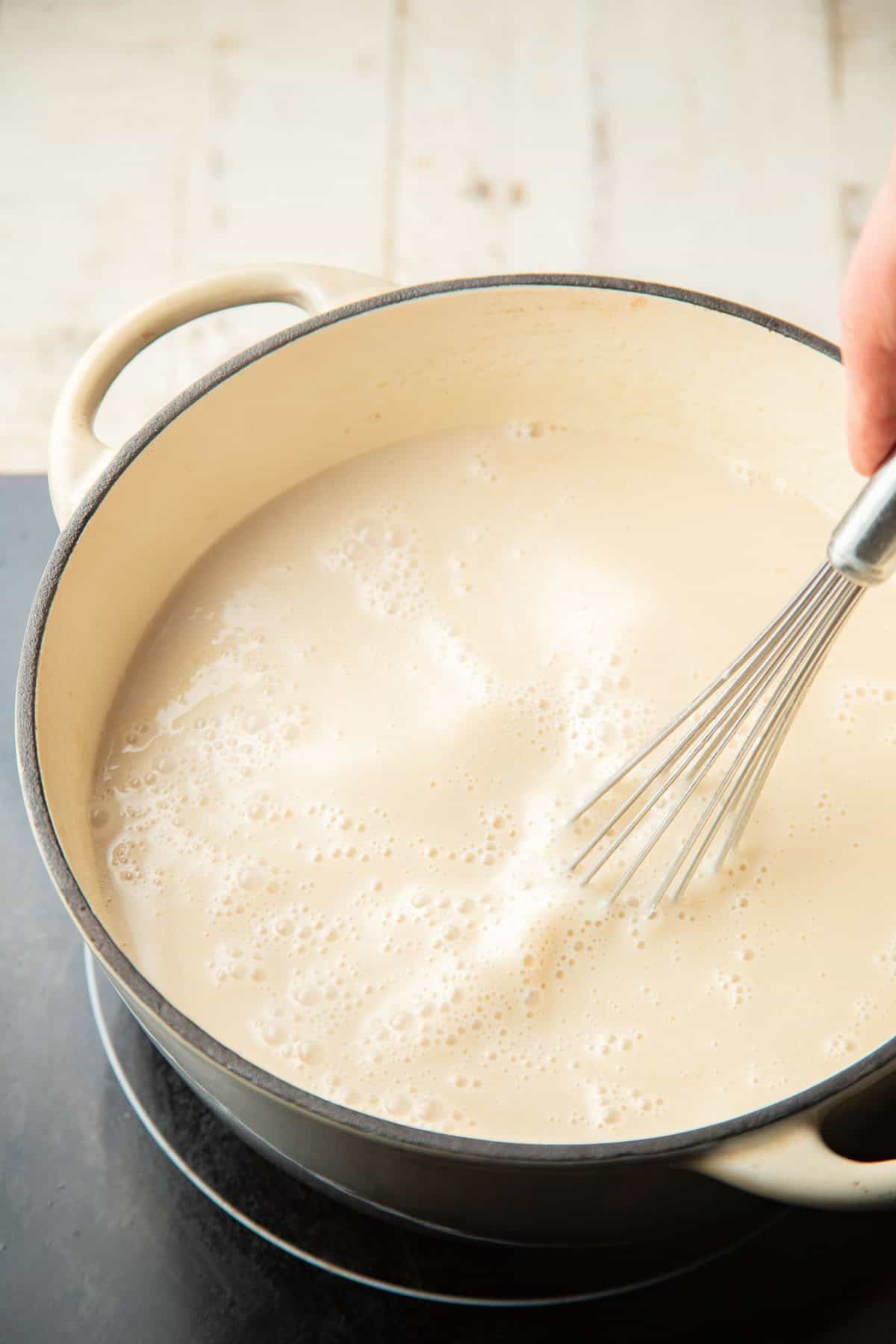 Hand whisking vegan ice cream base in a saucepan.