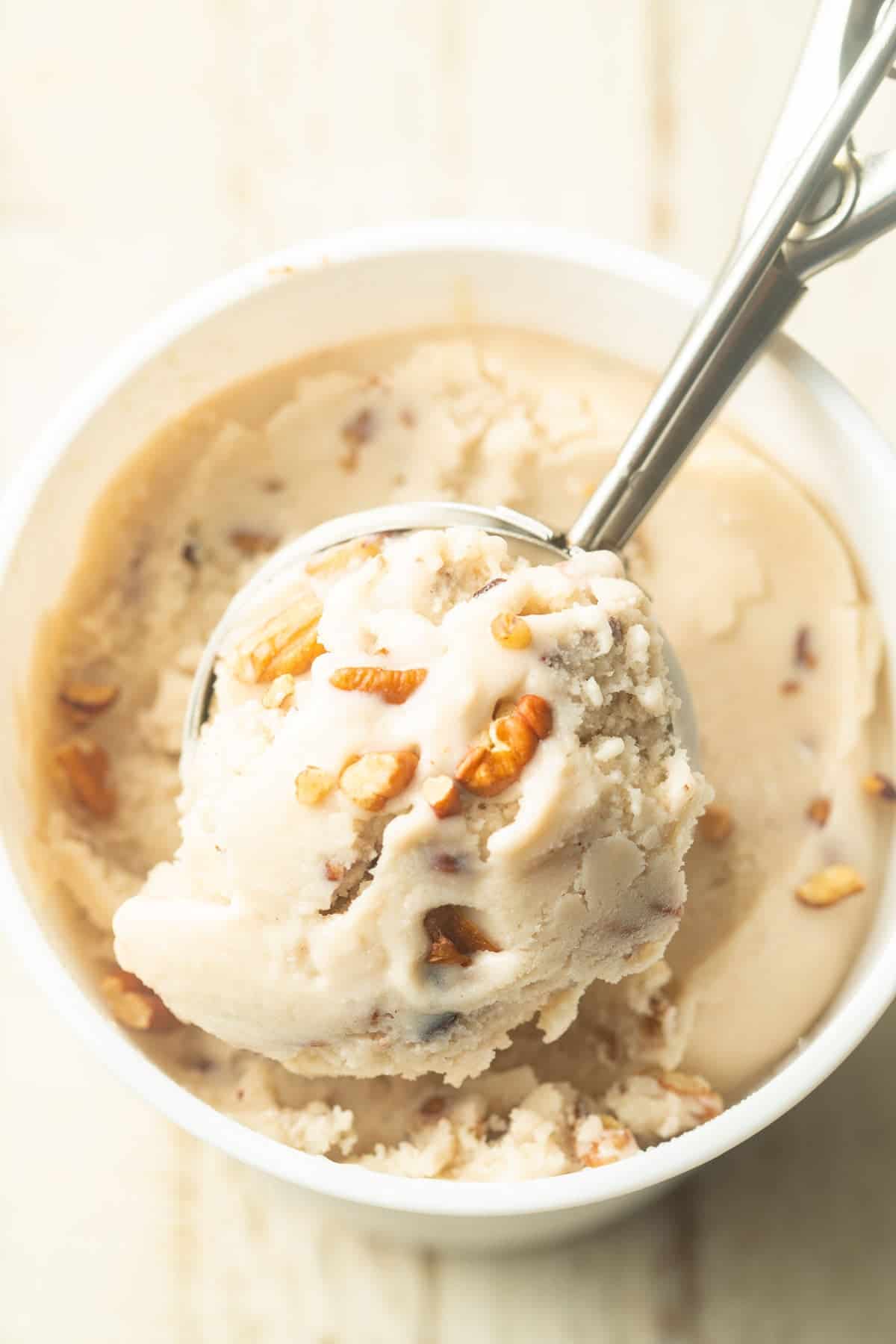 Container of Vegan Butter Pecan Ice Cream with ice cream scoop.