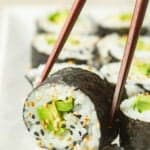 Chopsticks picking up a piece of Avocado Sushi from a dish.