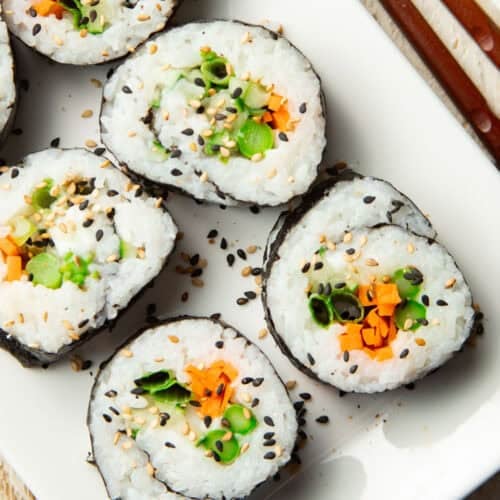 Vegan Cream Cheese & Veggie Sushi on a plate with chopsticks on the side.