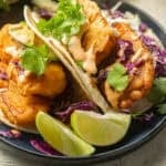 Vegan Beer-Battered Fish Tacos on a plate with lime wedges.