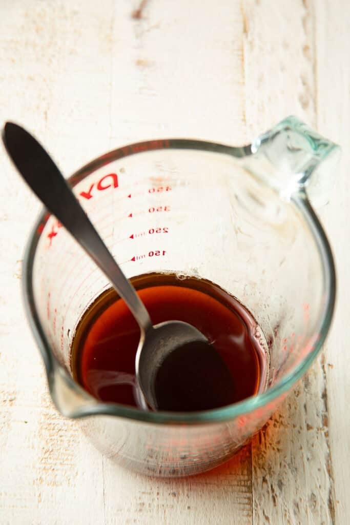 Vegan Agedashi Tofu sauce in a measuring cup with spoon.