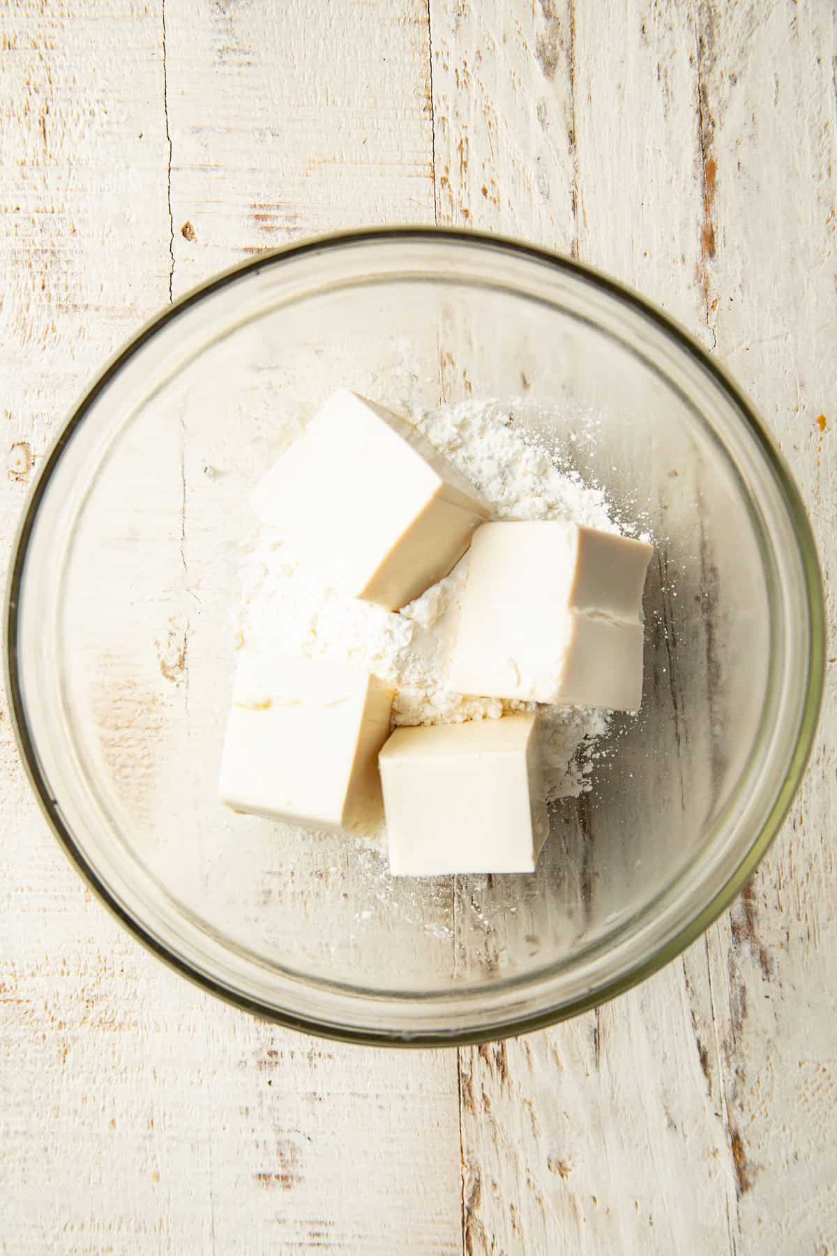 Silken tofu cubes in a bowl of cornstarch.