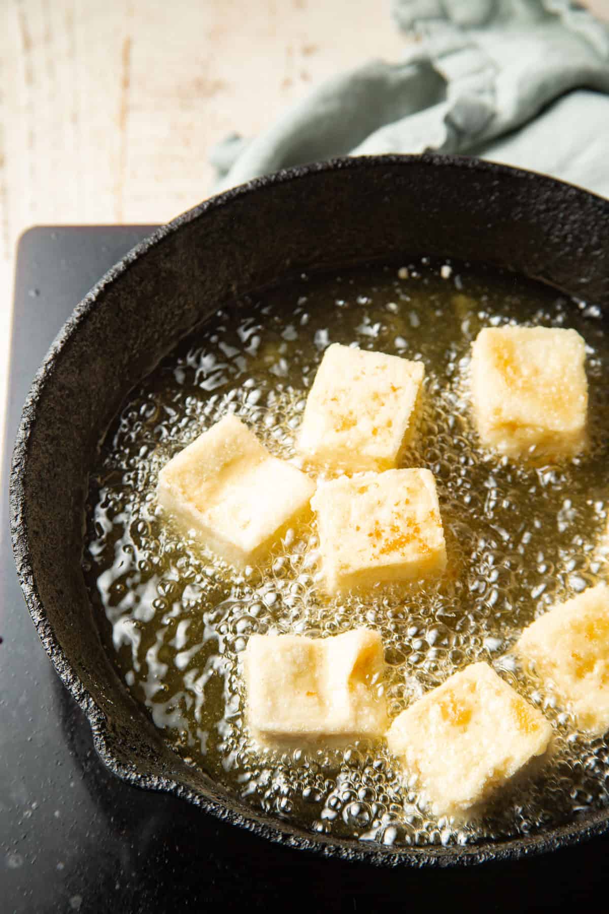 Vegan Agedashi Tofu cubes frying in oil.