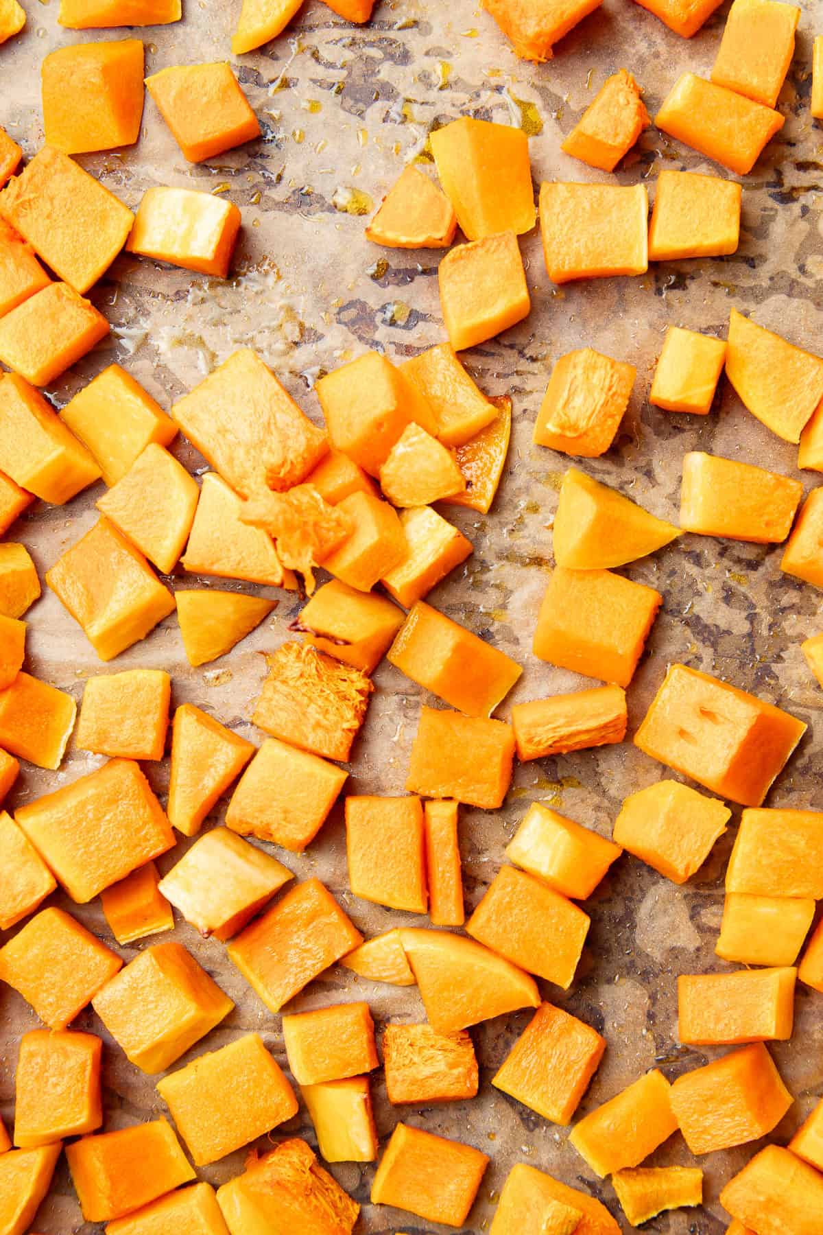 Roasted diced butternut squash on a baking sheet.