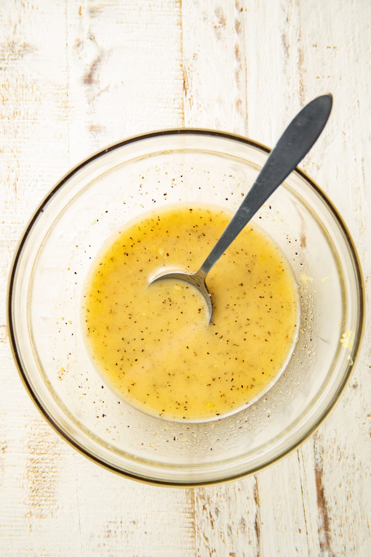 Lemon pepper glaze in a bowl with spoon.