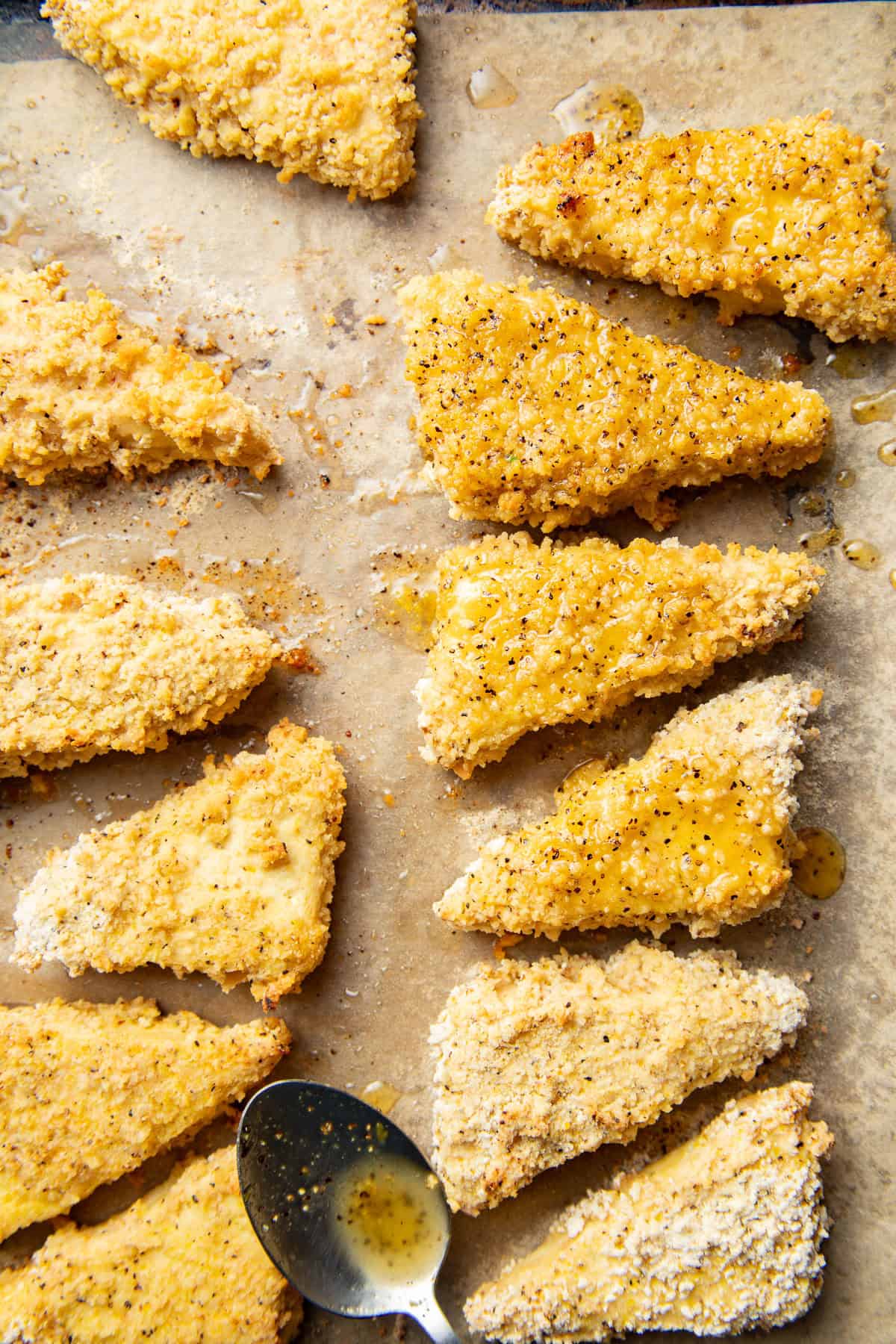 Spoon drizzling glaze over baked tofu bites on a baking sheet.