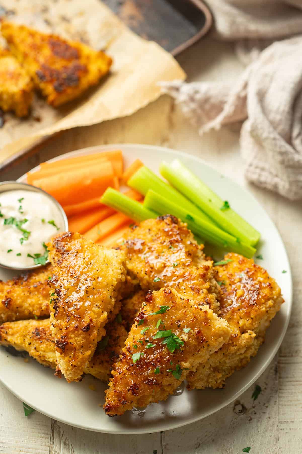 Plate of Lemon Pepper Tofu Wings with baking sheet in the background.