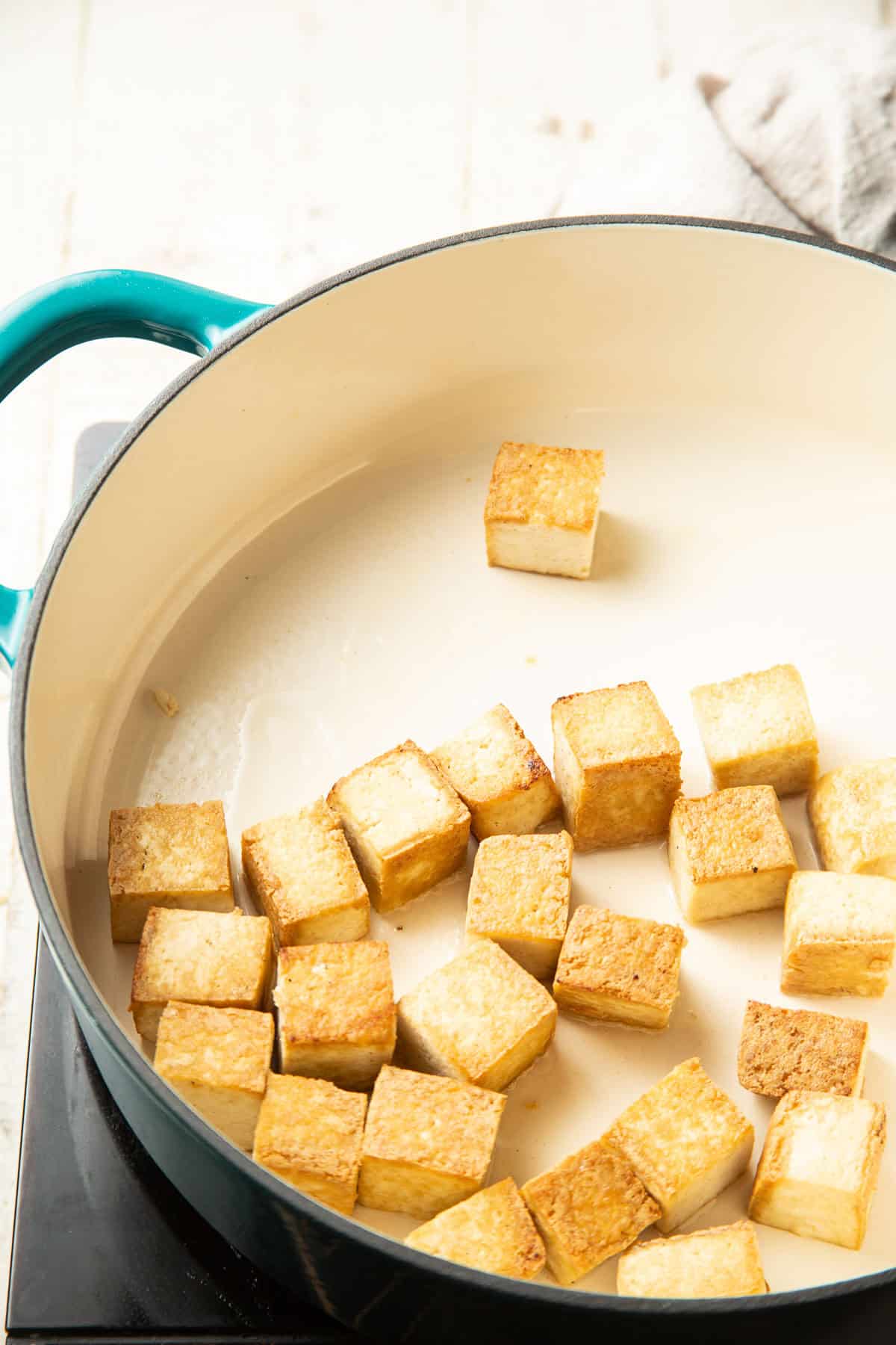 Tofu cubes cooking in a pot.